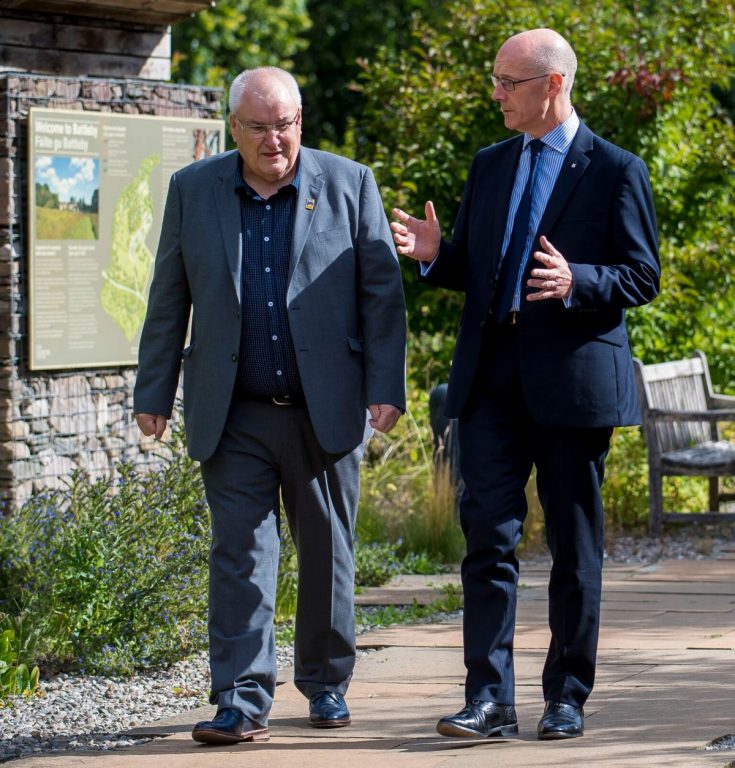 Picture: Ailean MacDonald, former Chair of Bòrd na Gàidhlig and John Swinney, former deputy First Minister walking on a path outdoors with John Swinney talking to Ailean MacDonald