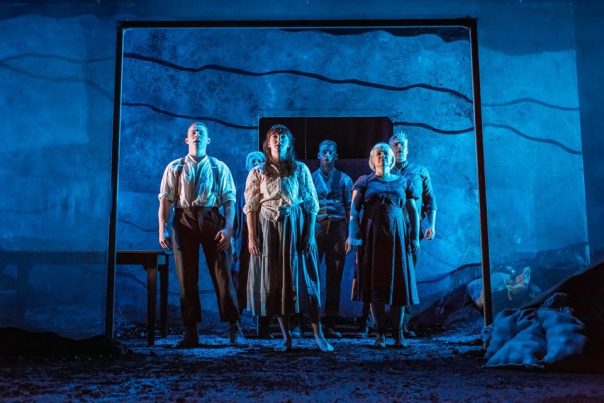 Picture: Six performers on stage in period clothing. The stage is dark with blue light projected onto them