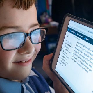 Picture: A young boy reading Gaelic text on a tablet