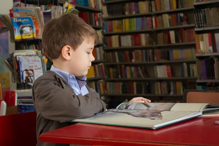 Picture: Child in library reading a book in a school uniform.