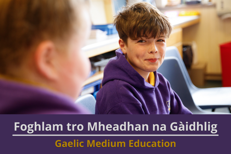 Picture: A boy in school uniform sitting in a classroom, smiling at the camera. Text reads 'Gaelic Medium Education'