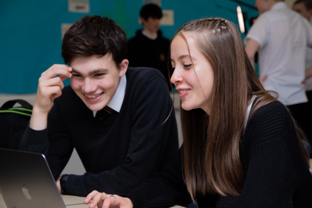 Picture: Two mid to late high school aged pupils in school uniform using a laptop in a classroom.